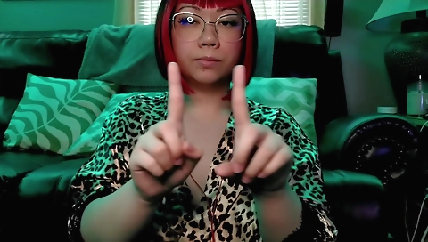 Red-haired girl in a red dress is practicing on a webcam